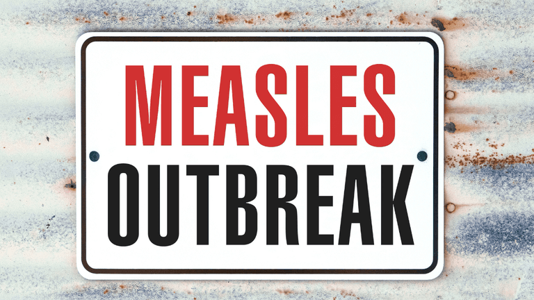 Sign reading "Measles Outbreak" against a weathered metal background.