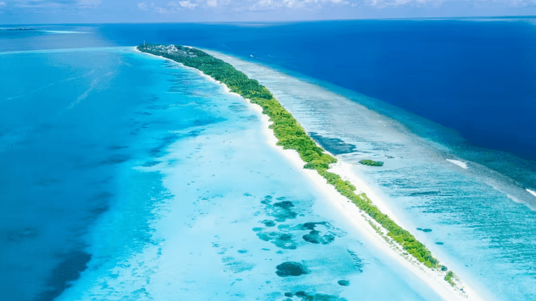 An aerial view of a serene Maldives island, showcasing turquoise waters, white sandy beaches, and lush greenery, highlighting the authentic local beauty.