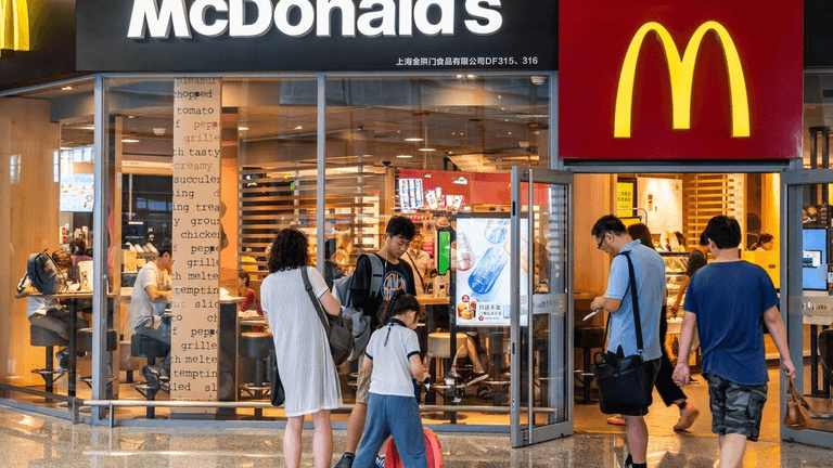 Crowd of people entering a McDonald's restaurant with bright signage and interior lights