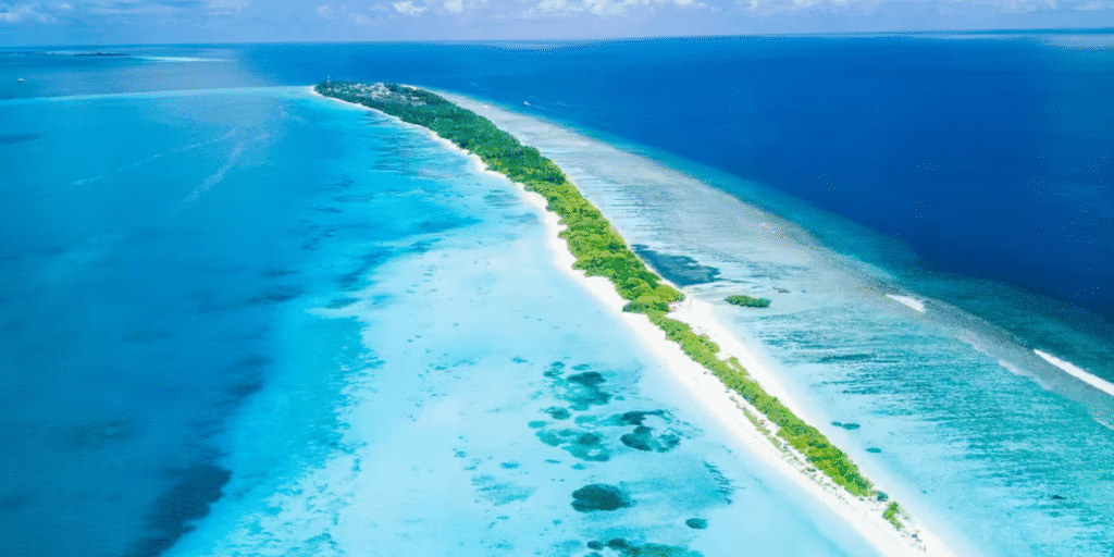 An aerial view of a serene Maldives island, showcasing turquoise waters, white sandy beaches, and lush greenery, highlighting the authentic local beauty.