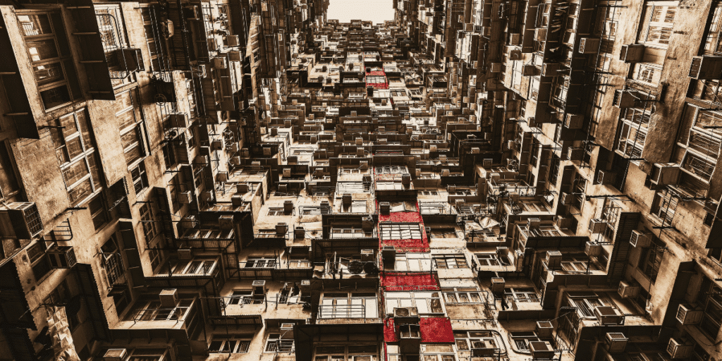Dense apartment buildings viewed upward, repeating balconies and windows forming abstract inner-city pattern with warm tones.