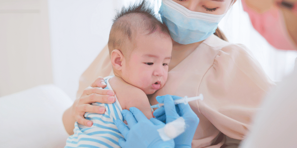 Global Childhood Vaccination Rates Improve, but Health Agencies Warn More Progress Is Needed Healthcare worker administers a routine vaccine to an infant while a caregiver holds the child.